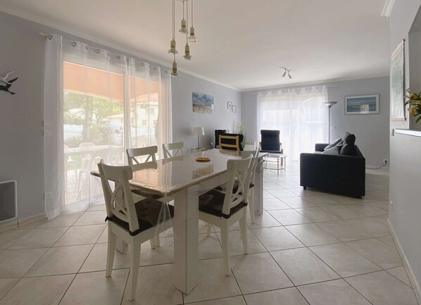A dining area with a table and chairs, a sofa, and a TV.