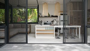 Une cuisine moderne dotée d’un îlot central, de portes vitrées et offrant une vue sur la verdure environnante.