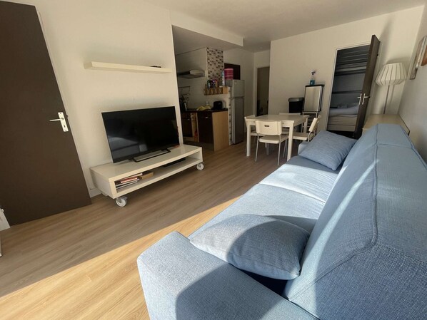 Ein modernes Wohnzimmer mit einer Couch, einem Fernseher und einem Essbereich.