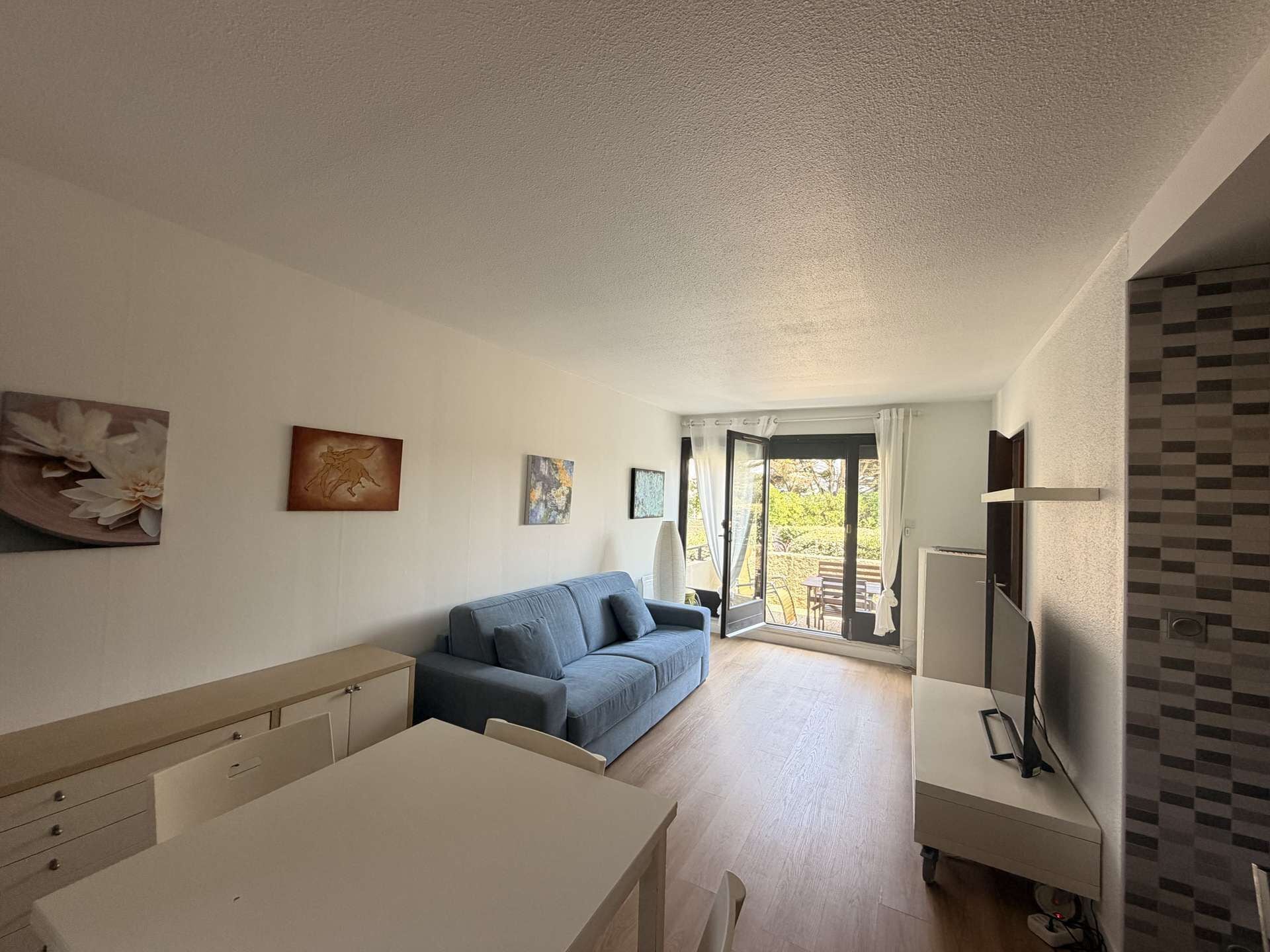 A modern living room with a sofa, a dining table, and artwork on the walls.