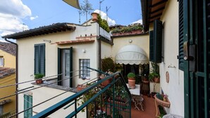 A residential building with a balcony, potted plants, a small table, and a door.