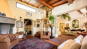 A spacious living room with a fireplace, leather sofas, a large rug, and a staircase leading to an upper level.