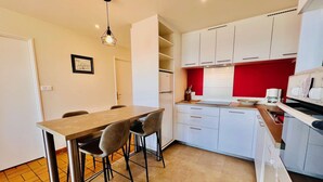 A compact kitchen with white cabinets, a wooden dining table, and two bar stools. - QUIBERON - 2 rooms of about 38m² for 4 people SEA VIEW (QUIBERON)