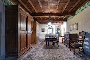 A hallway with wooden cabinets, a patterned rug, a table with chairs, and a chandelier.