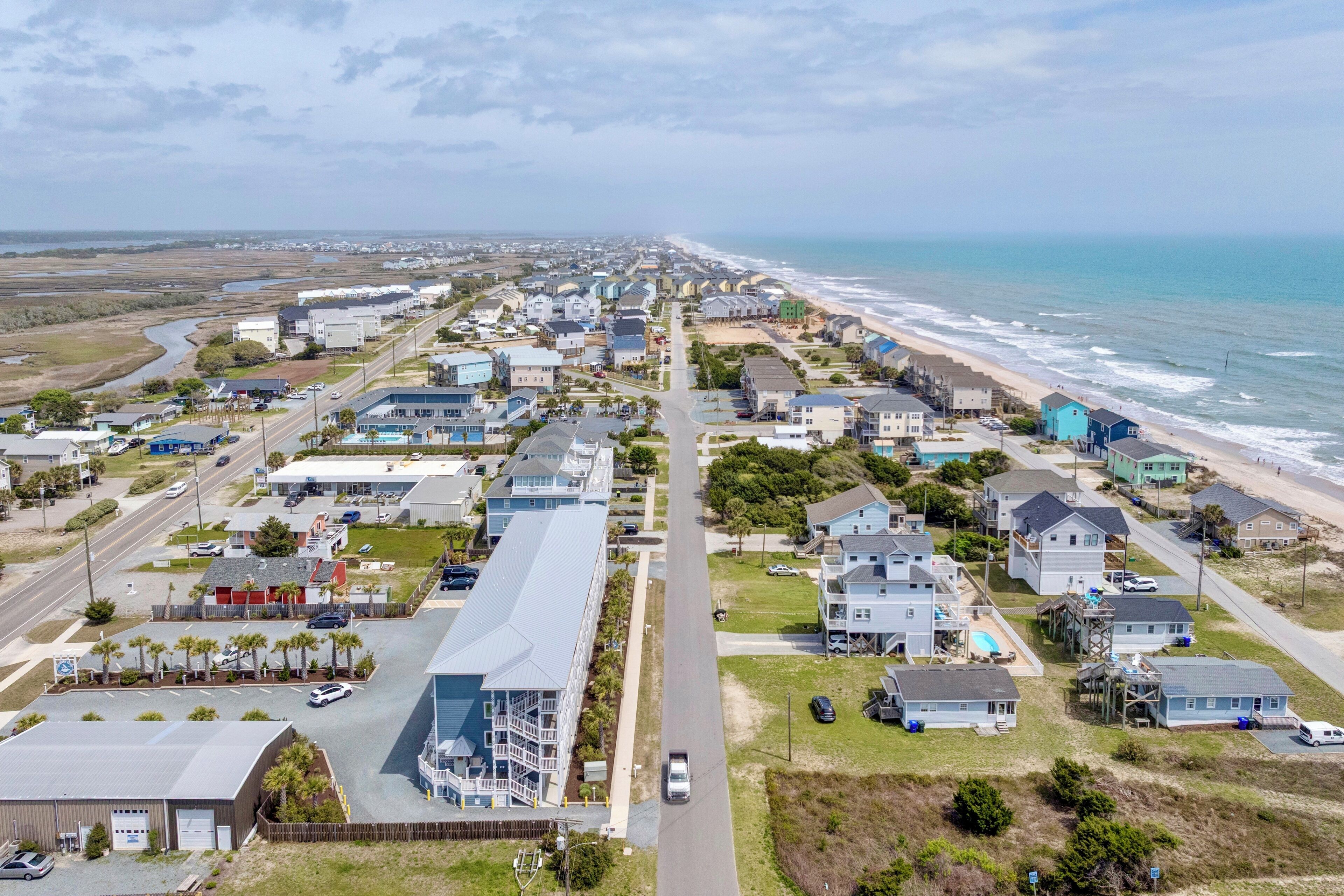 Vue aérienne d’une zone résidentielle côtière, avec des maisons, une route et une plage.