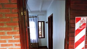 A wooden interior hallway with a brick wall, a wooden door, and a red and white striped sign on the wall.