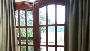 A wooden door with glass panels, beige curtains, and a wooden floor.