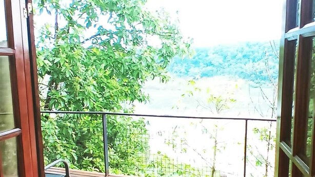 A wooden deck with a metal railing, leading to a glass door.