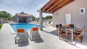 A pool area with lounge chairs and a table with chairs. - Villa mit Pool und Klimaanlage (Pula)