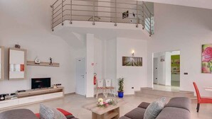 A spacious living area with a high ceiling, a balcony, a flat-screen TV, and a seating arrangement with sofas and a coffee table. - Villa mit Pool und Klimaanlage (Pula)