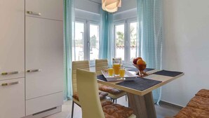 A modern dining area with a table set for two, a fruit bowl, and a tray with orange juice glasses. - Villa mit Pool und Klimaanlage (Pula)