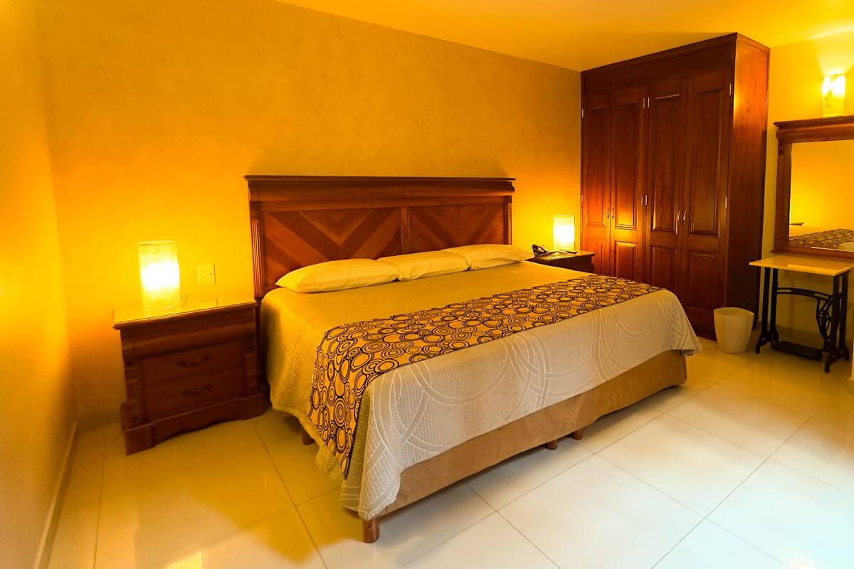 A bedroom with a bed, bedside tables, a wardrobe, and a mirror.