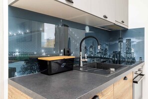 Een moderne keuken met een stadsgezicht muurschildering, een houten aanrecht en een zwart opbergmeubel.