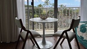 Una habitación con un ventanal grande, dos sillas, una mesita y un cuenco decorativo sobre la mesa.