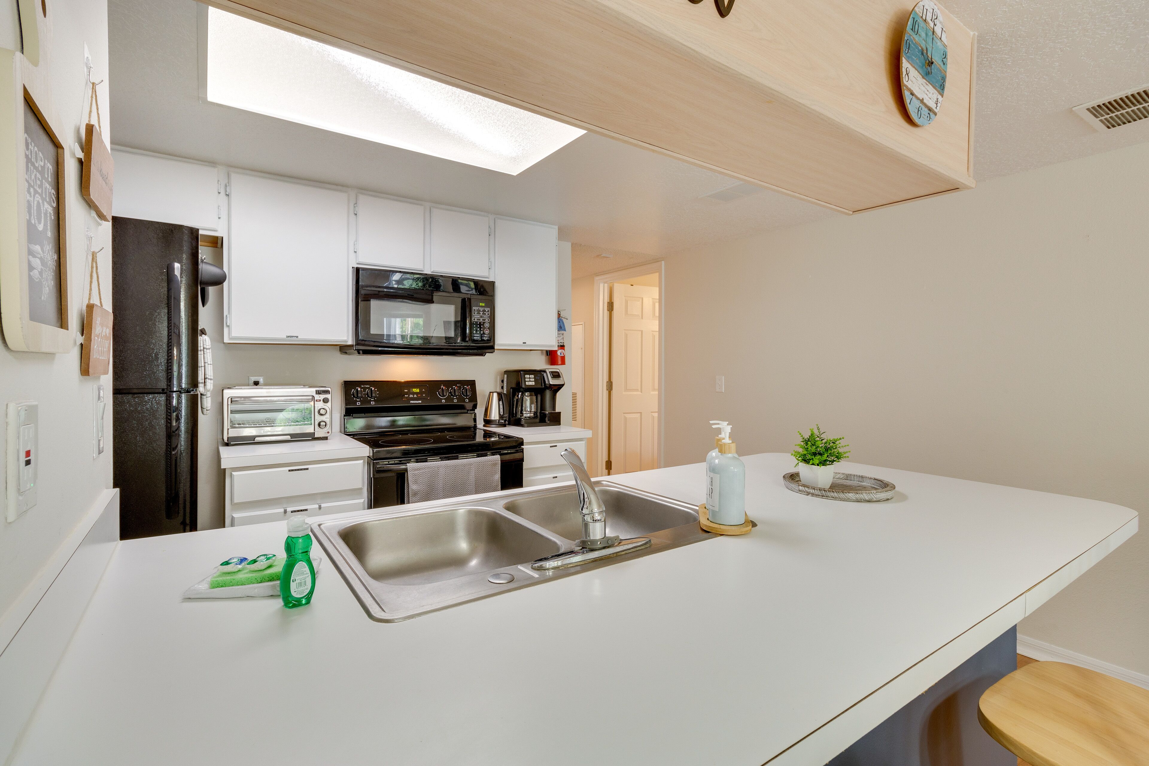 A modern kitchen with white cabinets, a stainless steel sink, a microwave, and a toaster.