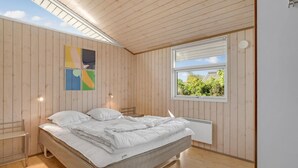 A bedroom with a wooden ceiling, a large bed with white bedding, a window with a view of greenery, and a radiator. - Gorgeous home in Allingåbro with WiFi (Allingåbro)