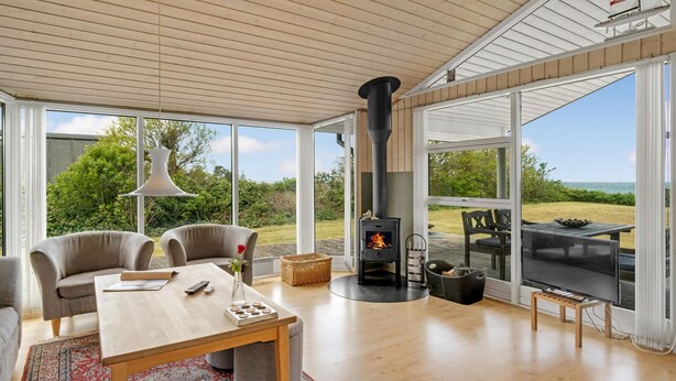 A cozy living room with a large window, a fireplace, comfortable seating, and a view of the outdoors. - Gorgeous home in Allingåbro with WiFi (Allingåbro)