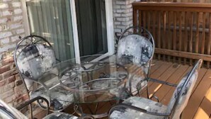 A glass-top table with metal chairs, a brick wall, and a wooden deck. - Beautifully Renovated DuPont Circle Studio (Washington)