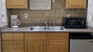 Una cocina con armarios de madera, un lavamanos doble, una cafetera, un microondas y un lavavajillas.
