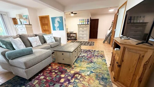 A living room with a sofa, coffee table, wooden cabinet, and a colorful rug.