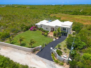 A large, single-story house with a paved driveway and a well-maintained lawn. - Villa Okeanos Anguilla (Shoal Bay Village)