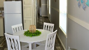 A dining area with a round table, white chairs, and a decorative centerpiece. - Sum Beaches Paradise Cottage 1 (Navarre)