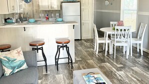A compact living space with a kitchenette, a dining area, and a seating area with a sofa and ottoman.