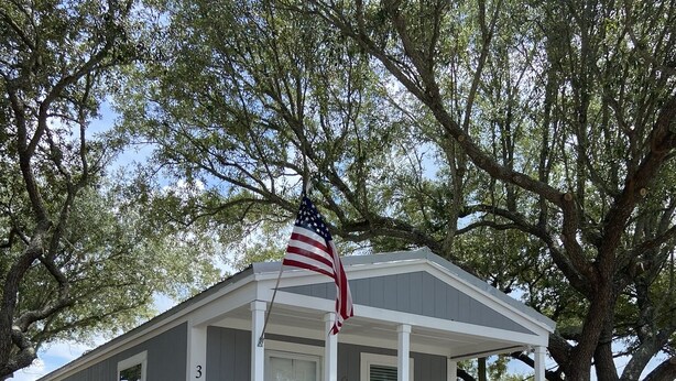 A single-story mobile home with a porch and a staircase leading to the entrance.