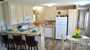 Une cuisine avec des meubles en bois, un réfrigérateur blanc, un four à micro-ondes et un coin repas comprenant une table et des chaises.
