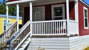 A red and white house with a porch, a door, and a window.