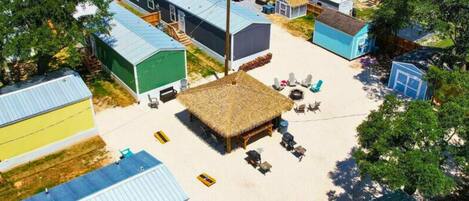 A cluster of mobile homes with a central communal area featuring a thatched-roof structure and outdoor seating.