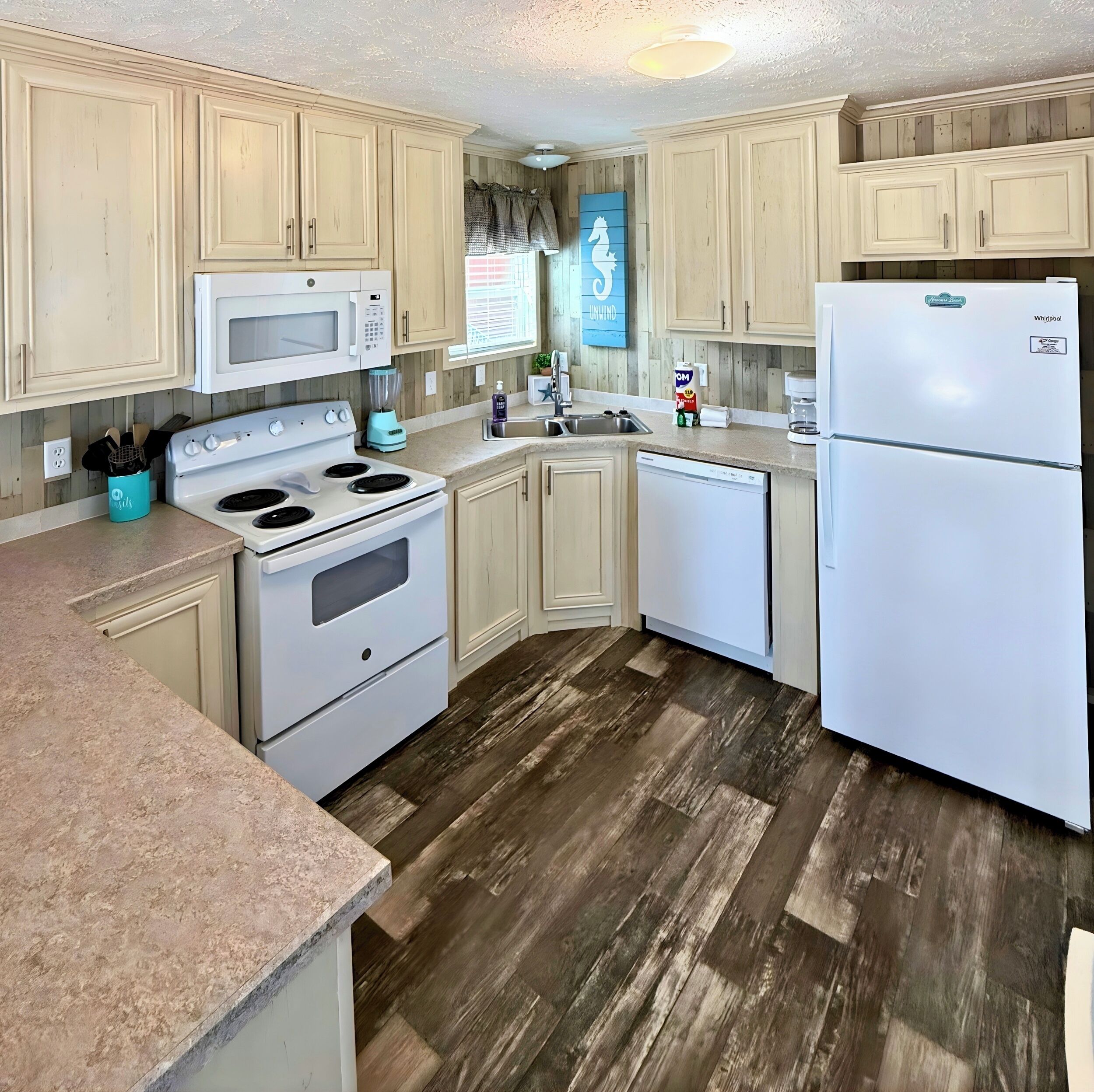 A kitchen with light wooden cabinets, a white refrigerator, a stove, and a microwave.