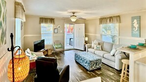 Un salon comprenant un téléviseur, un canapé, une table basse et un coin repas avec une table et des chaises.