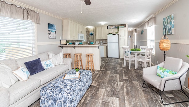A modern kitchen with white cabinets, a white refrigerator, and a dining area with white chairs and a table. - Sum Beaches Paradise Cottage 9 (Navarre)