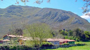 A rural landscape with a mountain in the background, a fenced field, and a building with a red roof. - Apto La Espina 1 - rural apartment in Celada (Villaviciosa) | 4 guests (Celada)