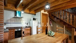A wooden dining table with chairs, a kitchen area with a microwave, and a staircase. - Apto La Espina 1 - rural apartment in Celada (Villaviciosa) | 4 guests (Celada)