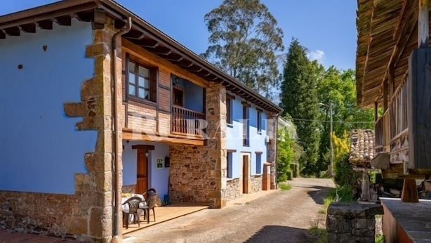 A traditional stone building with a balcony, a door, and a small outdoor seating area. - Apto La Espina 1 - rural apartment in Celada (Villaviciosa) | 4 guests (Celada)