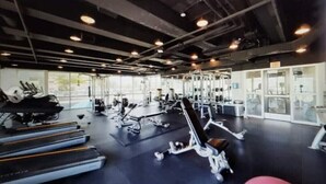 A gym with treadmills, weight machines, and a mirrored wall.
