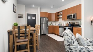 Una cocina moderna con armarios de madera, electrodomésticos de acero inoxidable y una zona de comedor con mesa y sillas.