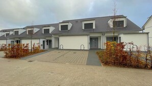 Une rangée de bâtiments modernes, de plain-pied, dotés d’un toit plat et d’un petit porche à l’avant.