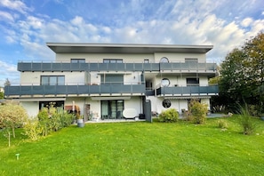 A modern two-story house with a flat roof, large windows, and a balcony. - "Experience an unforgettable vacation in the Achterwasserblick vacation apartment!" - (Loddin)