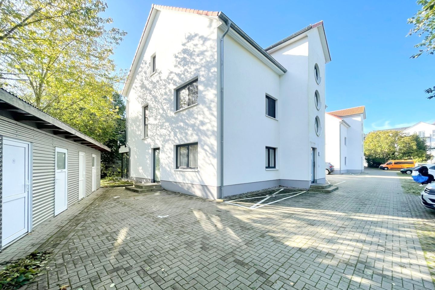 Un bâtiment moderne à deux étages, doté d’un toit plat et de murs extérieurs blancs.