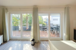 A spacious room with large sliding glass doors leading to an outdoor deck. - Relaxed vacation in the Strandstraße: Your dream home by the sea! - (Loddin)