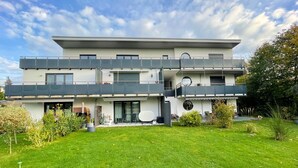 Un immeuble résidentiel moderne à deux étages, doté d ’un toit plat, de grandes fenêtres et d’un balcon.