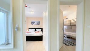 Une chambre d’hôtel avec un lit, un petit bureau et une vue sur le couloir.