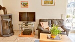 Un salon avec une cheminée, un téléviseur posé sur un meuble en verre, un canapé en cuir et deux tableaux encadrés accrochés au mur.