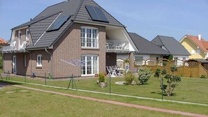 Une maison à deux étages avec une façade en briques, des panneaux solaires sur le toit et une pelouse bien entretenue.