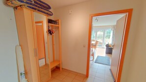 A hallway with a wooden wardrobe, a bench, and a door leading to a balcony. - Relax on 75 square meters in the Hansehuus, for 5 people, on the sunny island of Usedom. - (Zempin)
