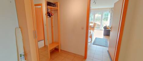 A hallway with a wooden wardrobe, a bench, and a door leading to a balcony.