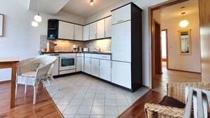 A modern kitchen with white cabinets, a built-in oven, and a dining area with wicker chairs.